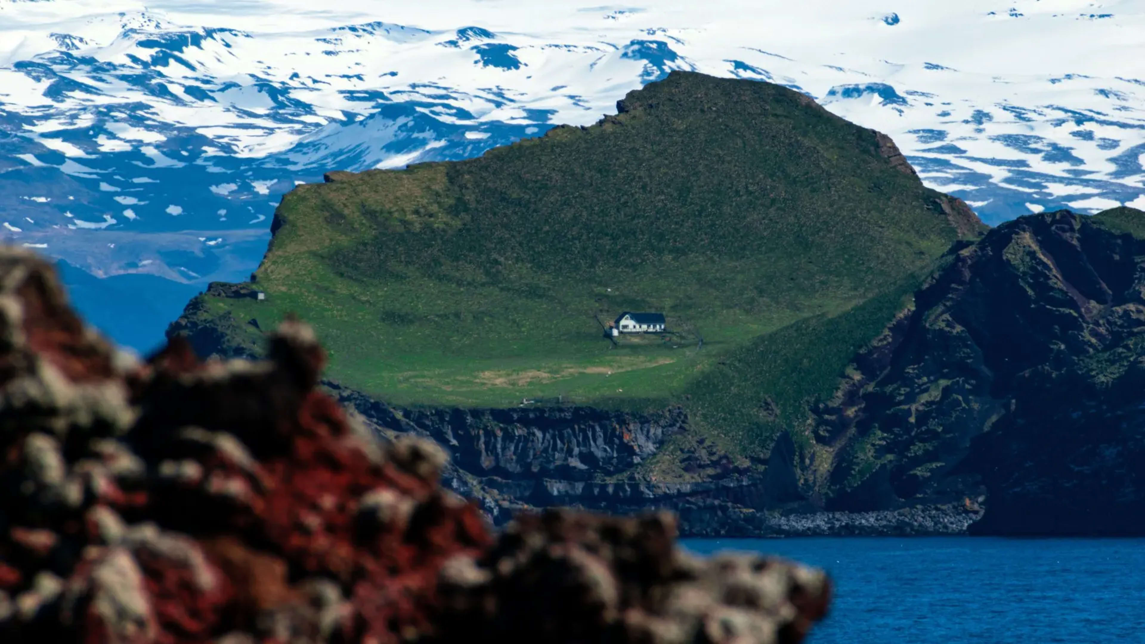 green sloping island with one house in the middle