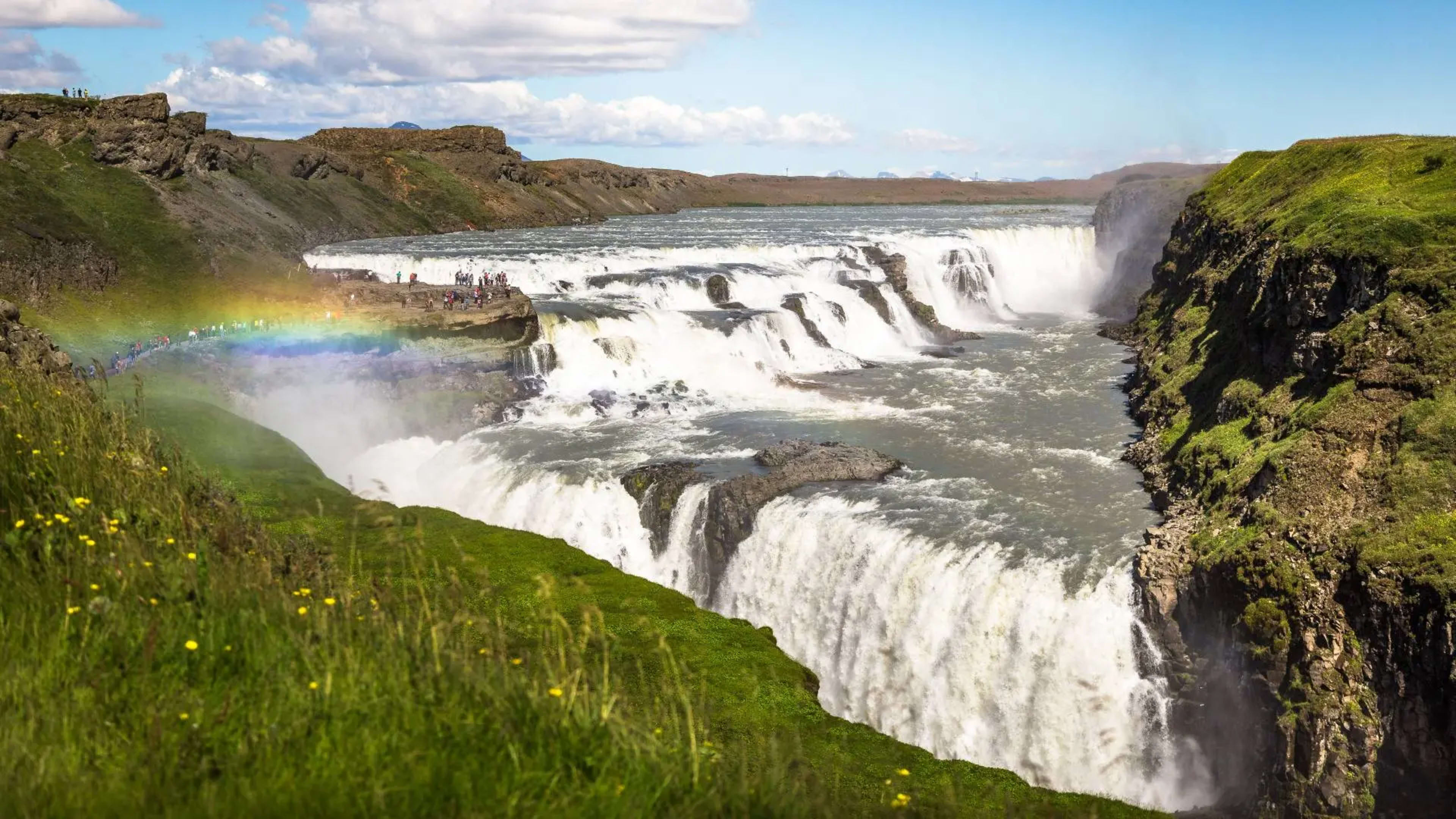 start of rainbow in the mist of multi-tiered waterfall in canyon