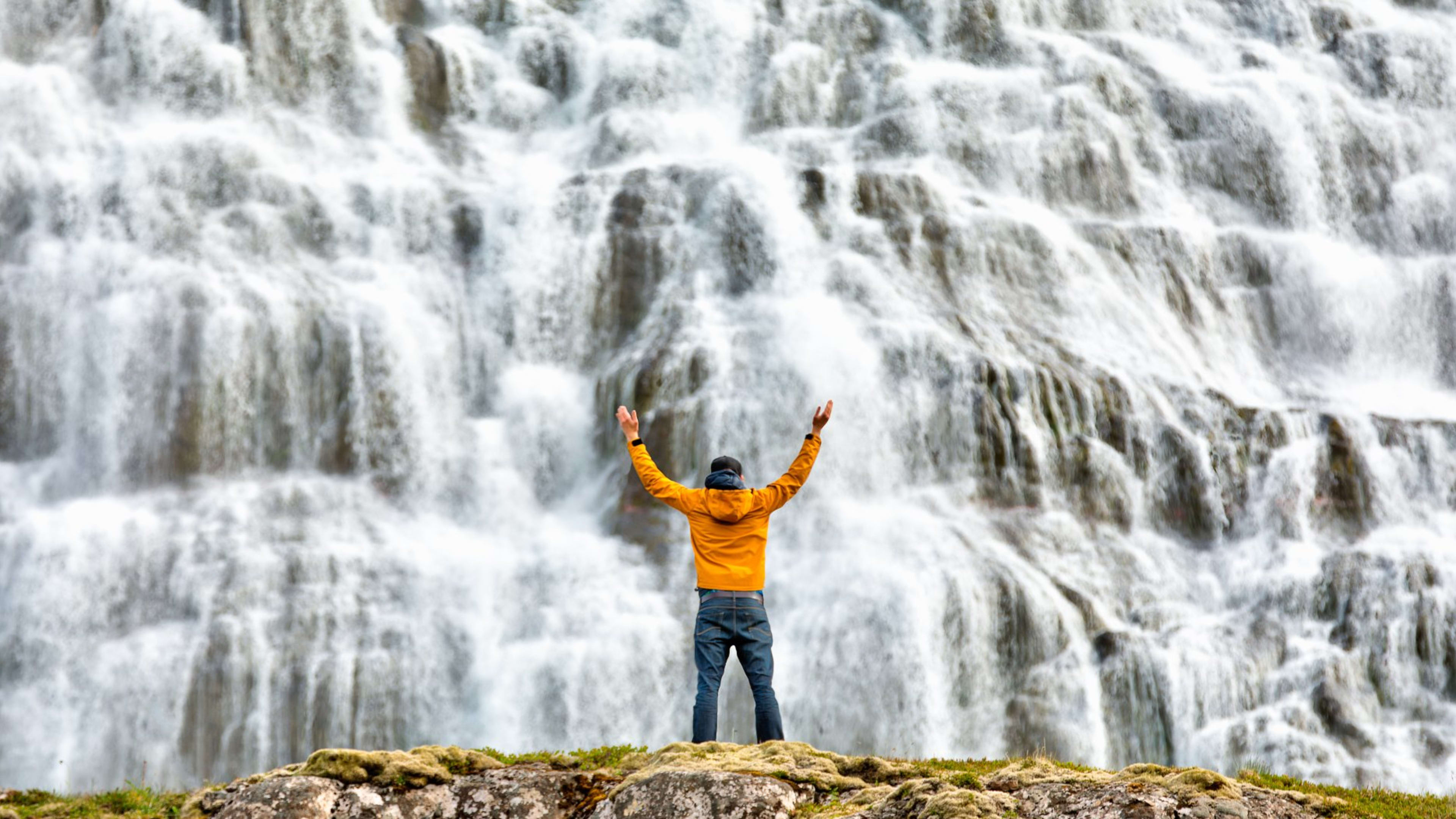 A man standing in front of the Dynjandi waterfall