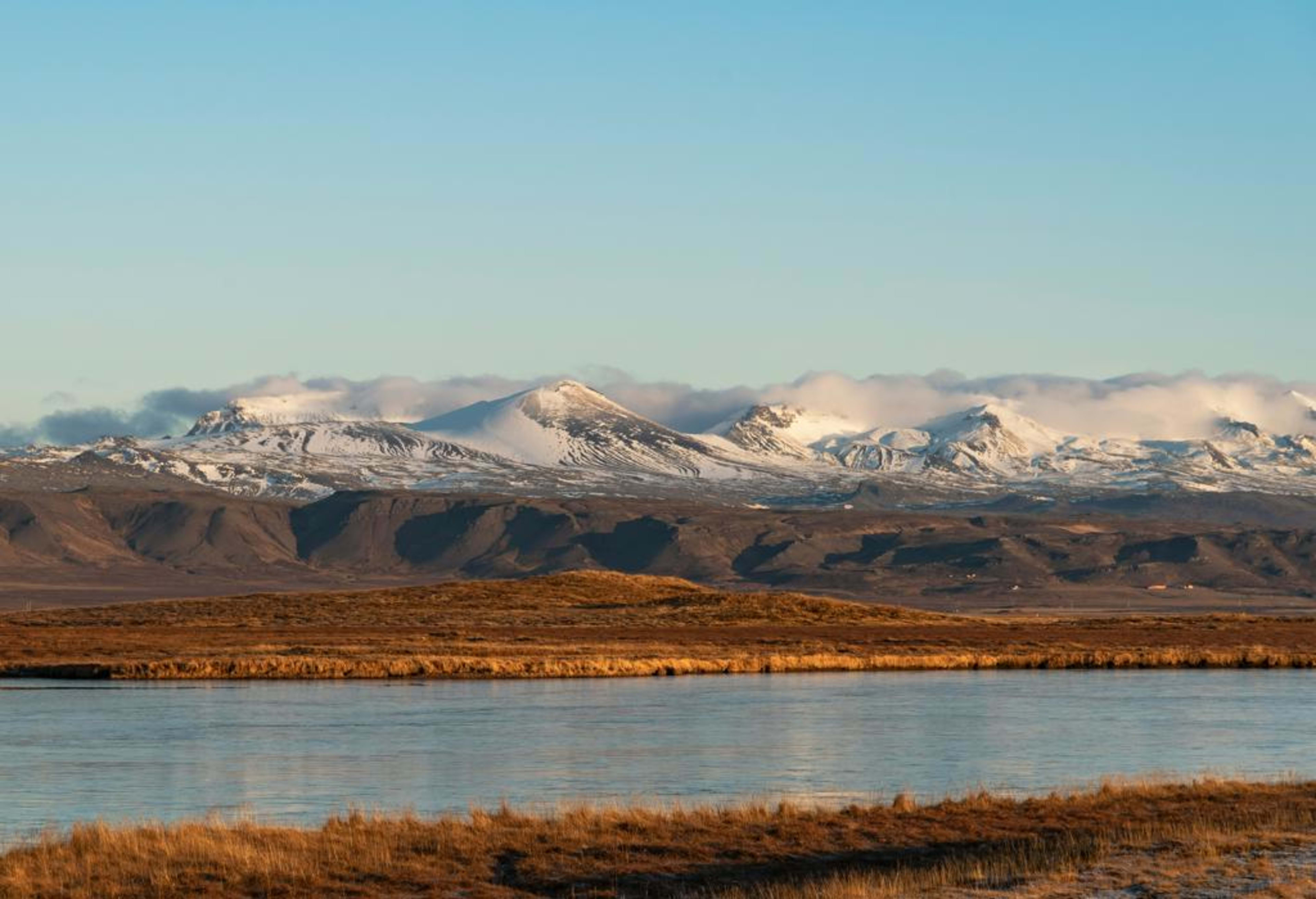 Snow-capped mountains reflected in calm coastal waters on the Snæfellsnes Peninsula in West Iceland.