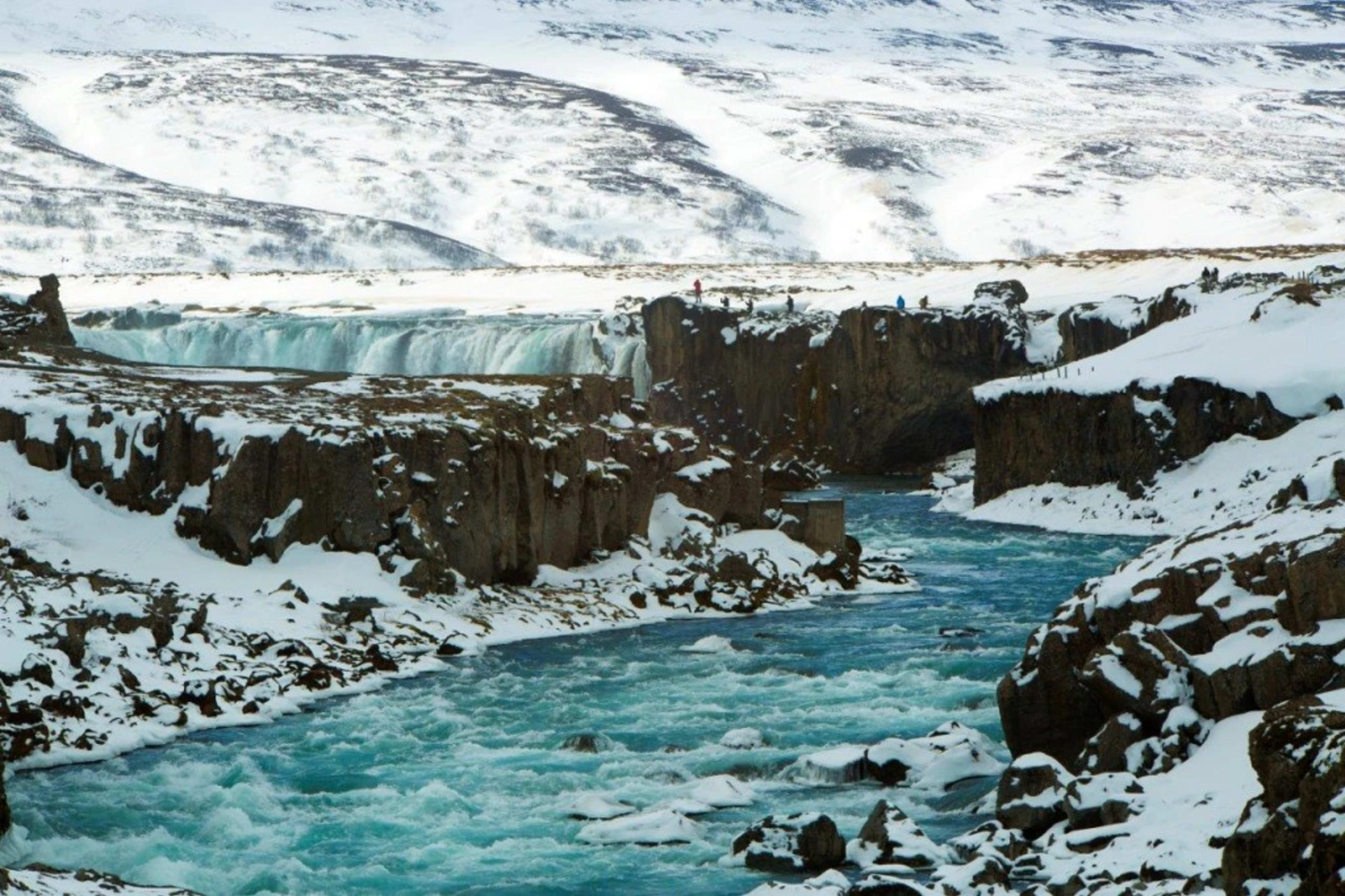 waterfall and river in the middle of snowy rocks and mountains