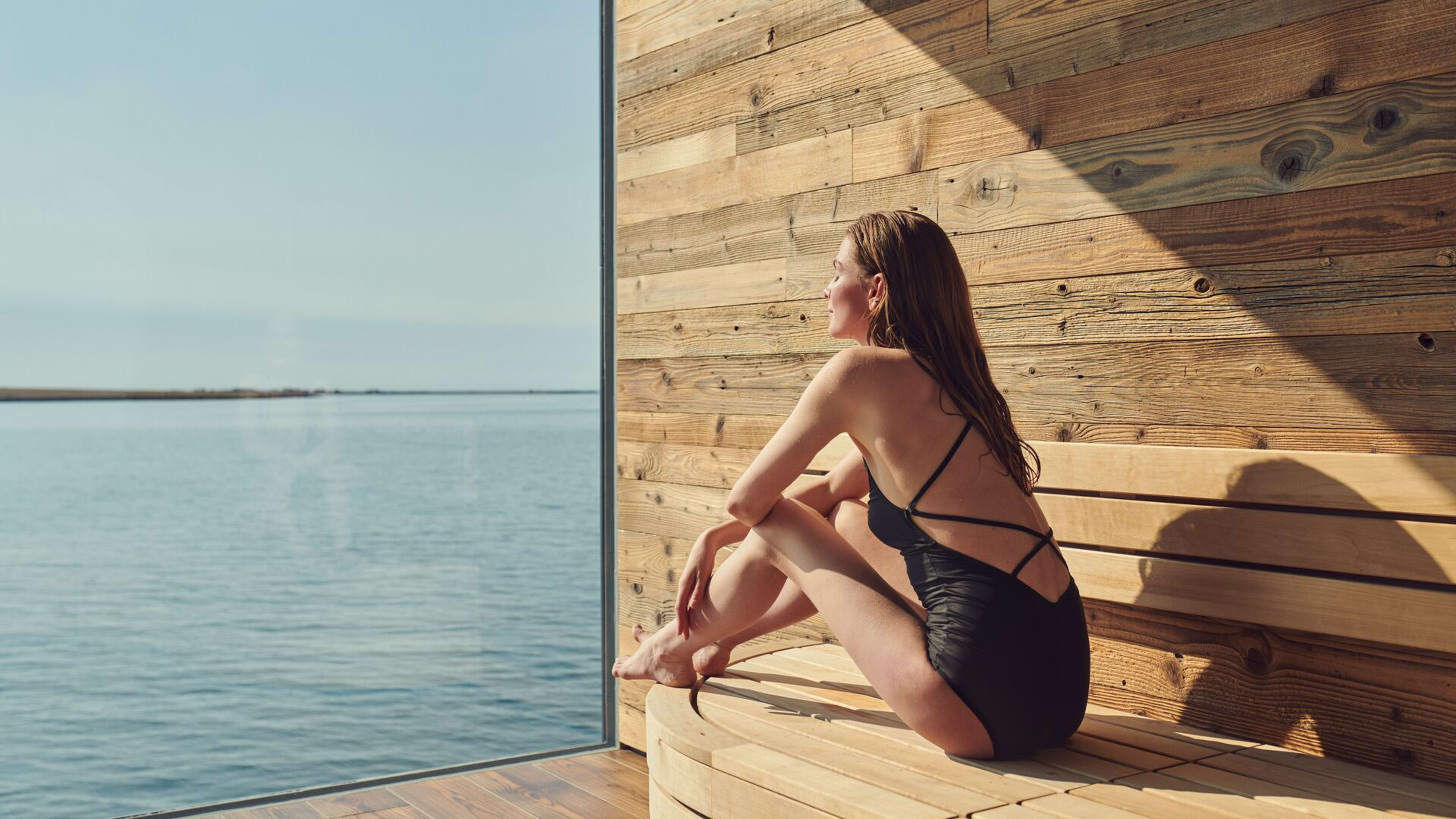 Woman sitting in the sauna with a sea view at Sky Lagoon.