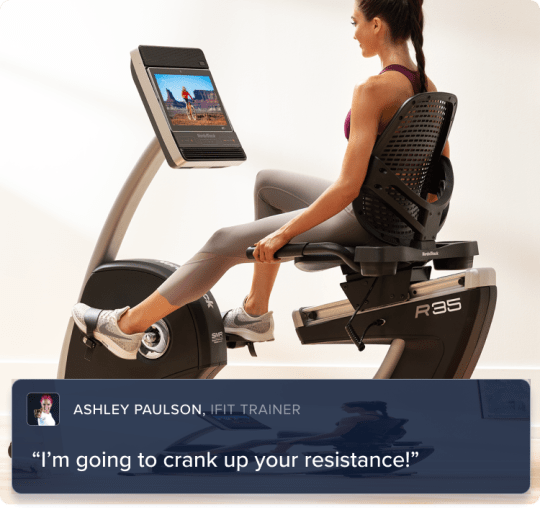 Woman biking on the machine. and looking at her iFIT trainer all from the comfort of a room in her home.