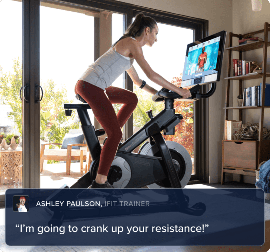 Woman riding on her bike, leaning and looking at her iFIT trainer.