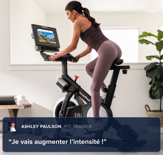 Woman riding on her bike, leaning and looking at her iFIT trainer.