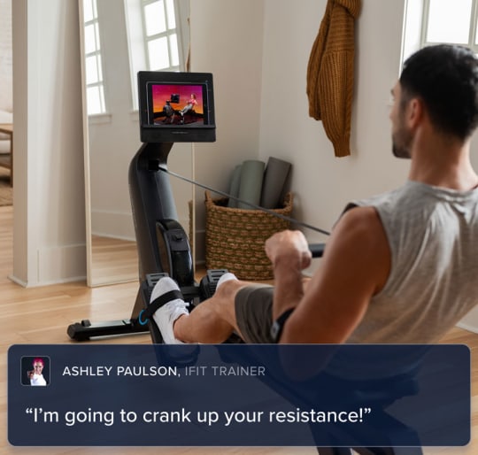 Woman pulling back the handle bars on her rower, her iFIT trainer virtually guiding her through a workout in her home.