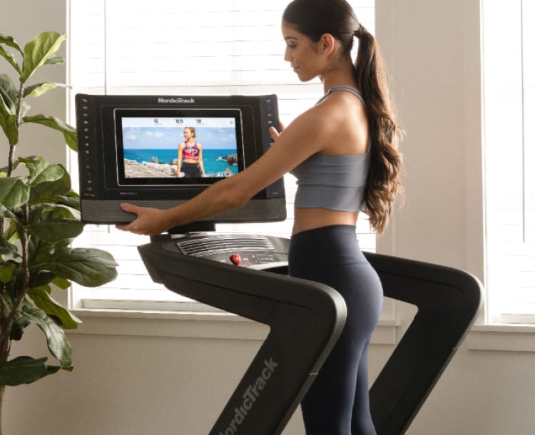 woman adjusting the 14 inch HD touchscreen on the commercial 1750 treadmill