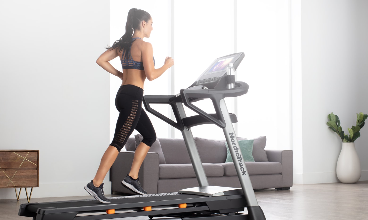 Woman jogging on treadmill doing a studio based workout.