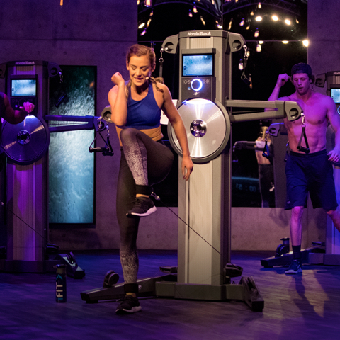 Trainer lifting knee in a studio class setting