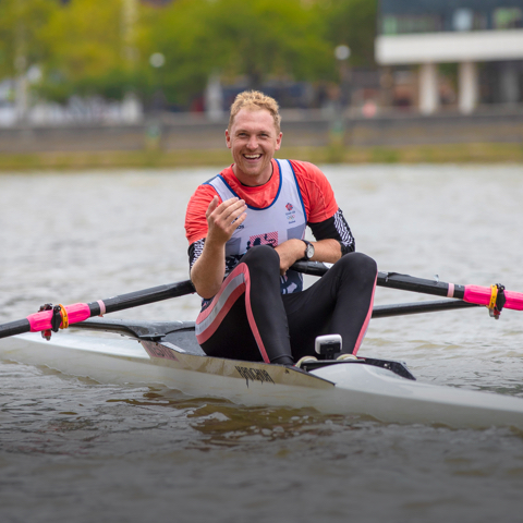 Trainer doing a row and lift workout, smiling at camera