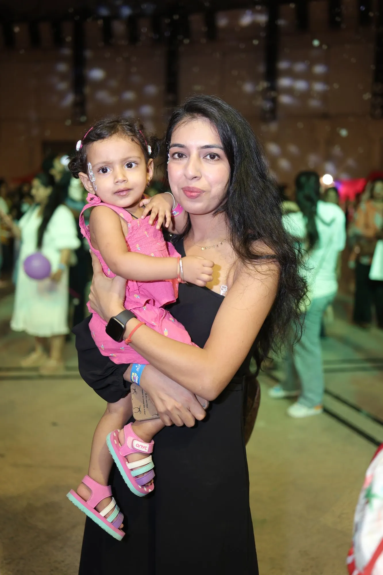 Mother holding her toddler daughter under party lights at Toddler Techno Party