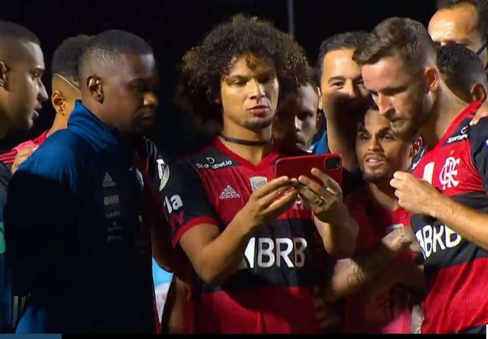 Jogadores do Flamengo assistem ao fim de jogo do Inter pelo celular, no campo do Morumbi