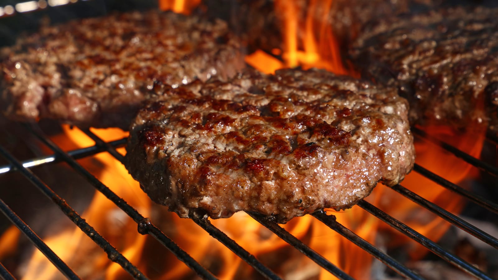 Hamburger patty being grilled on an open flame barbecue