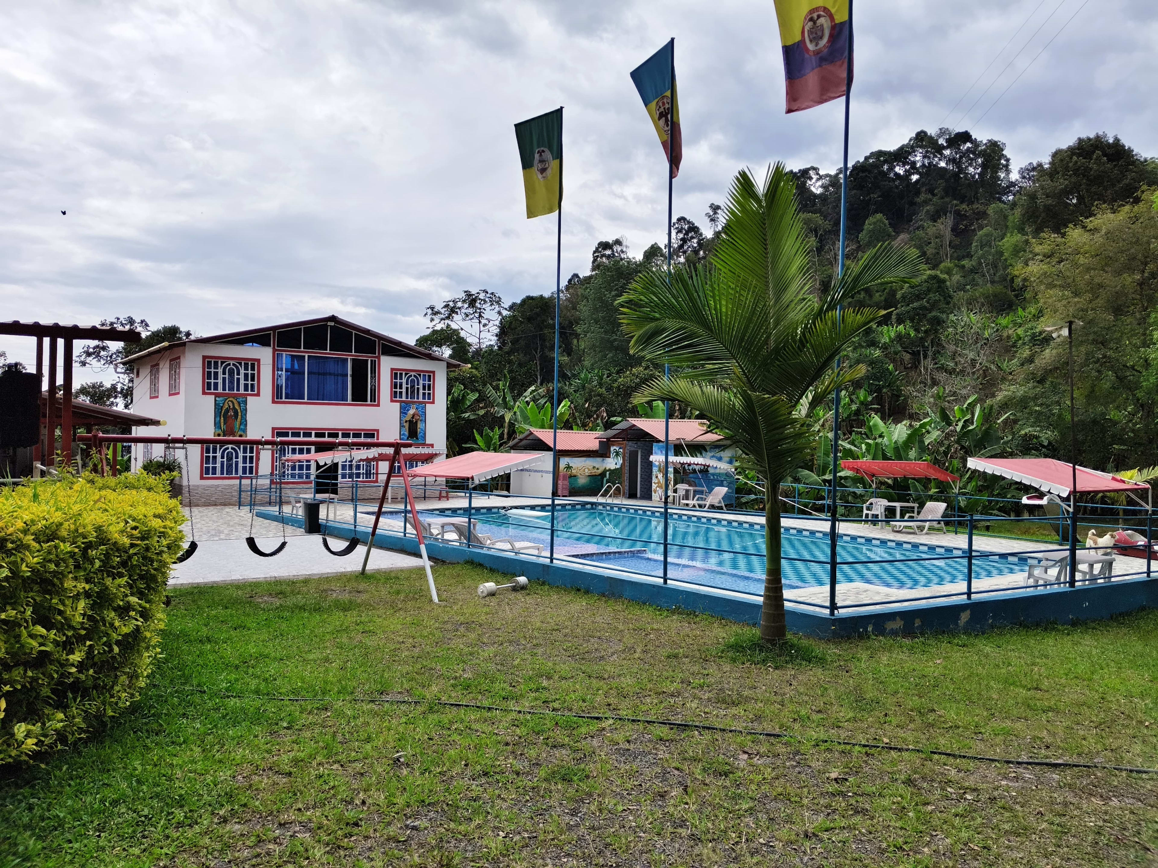 Vista de la piscina y las instalaciones de Brisas del Palmar Supateño, con palmeras y montañas al fondo
