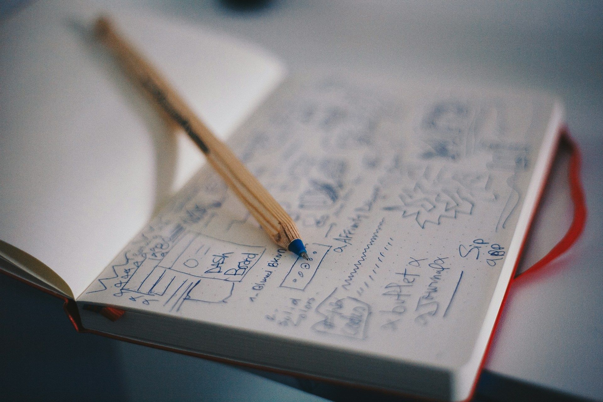 A close-up of a planning book with website page designs drawn out