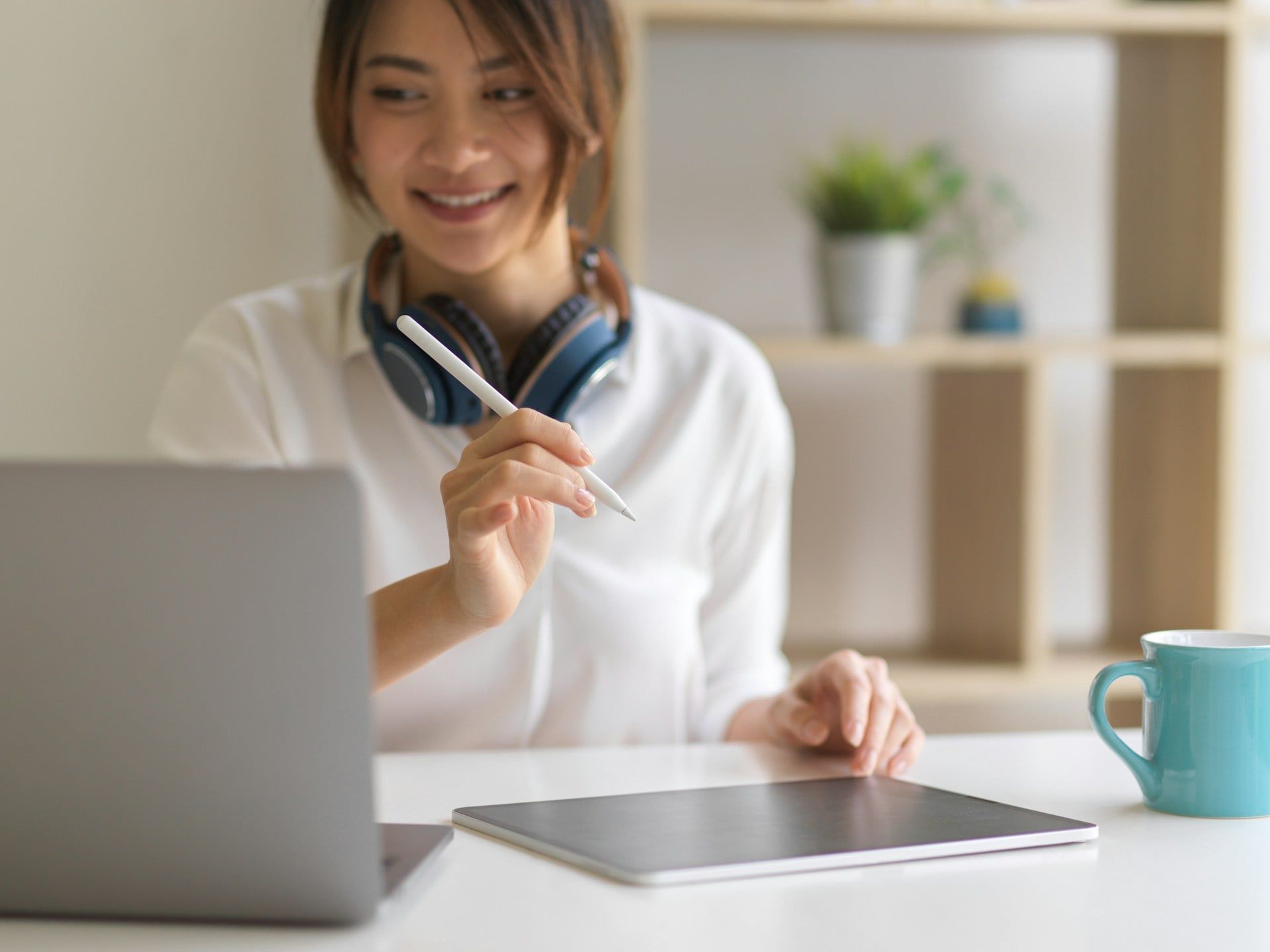 A woman smiles while using a user-friendly app on her laptop and tablet