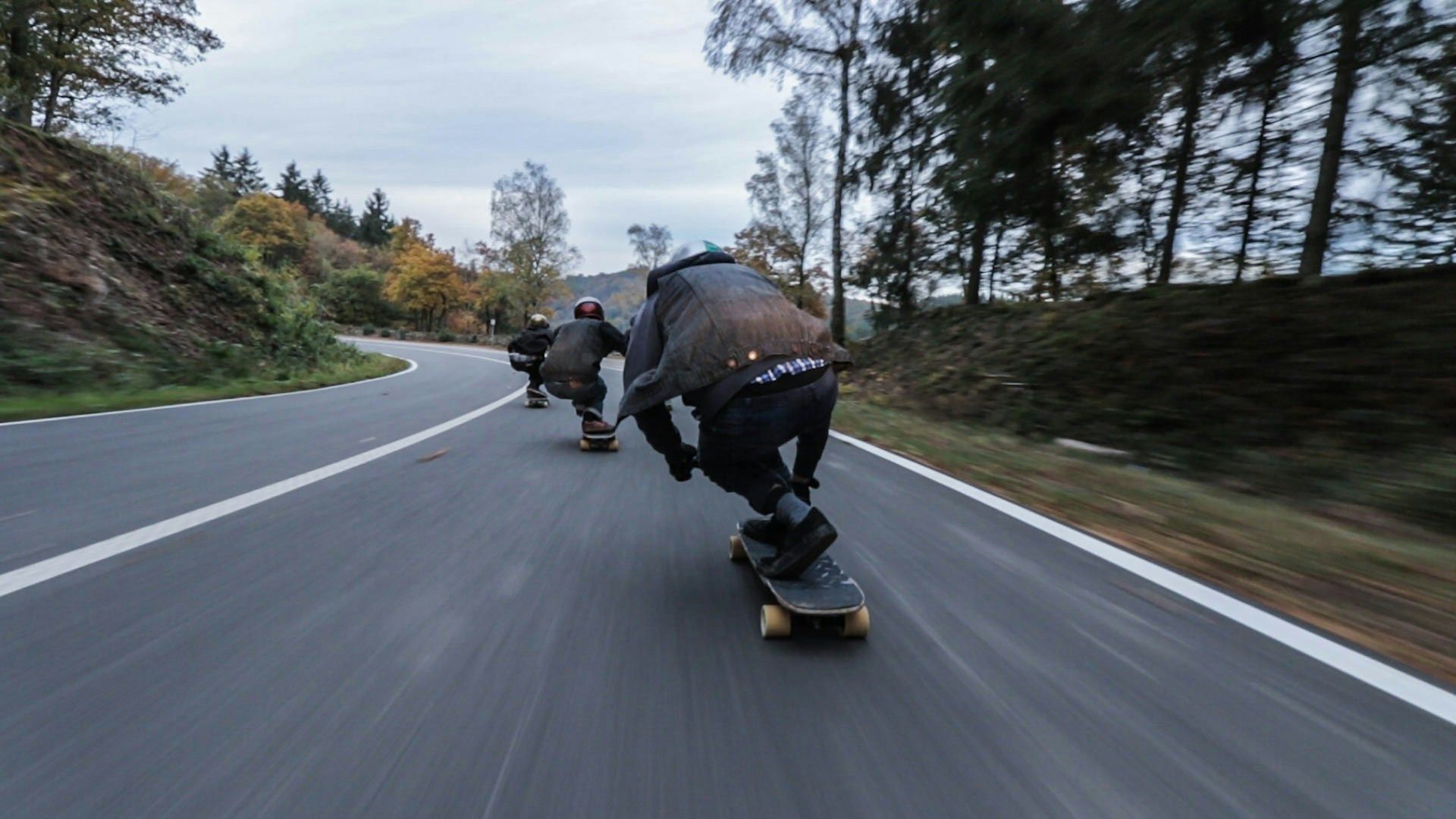 A group of skateboarders racing down a hill at high speeds