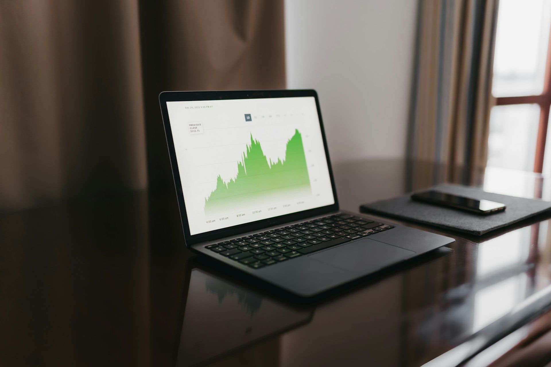 A laptop showing a green graph of data on an upward trend