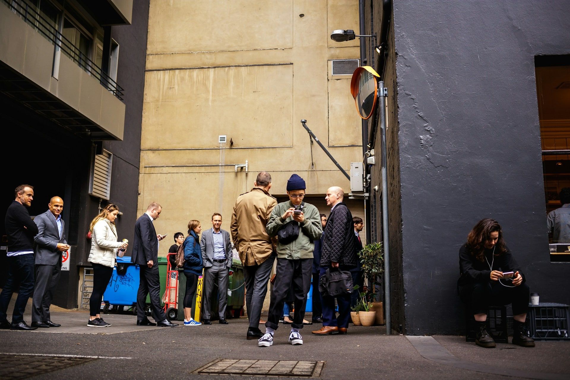 Lots of people queuing and standing on the street of all types and generations