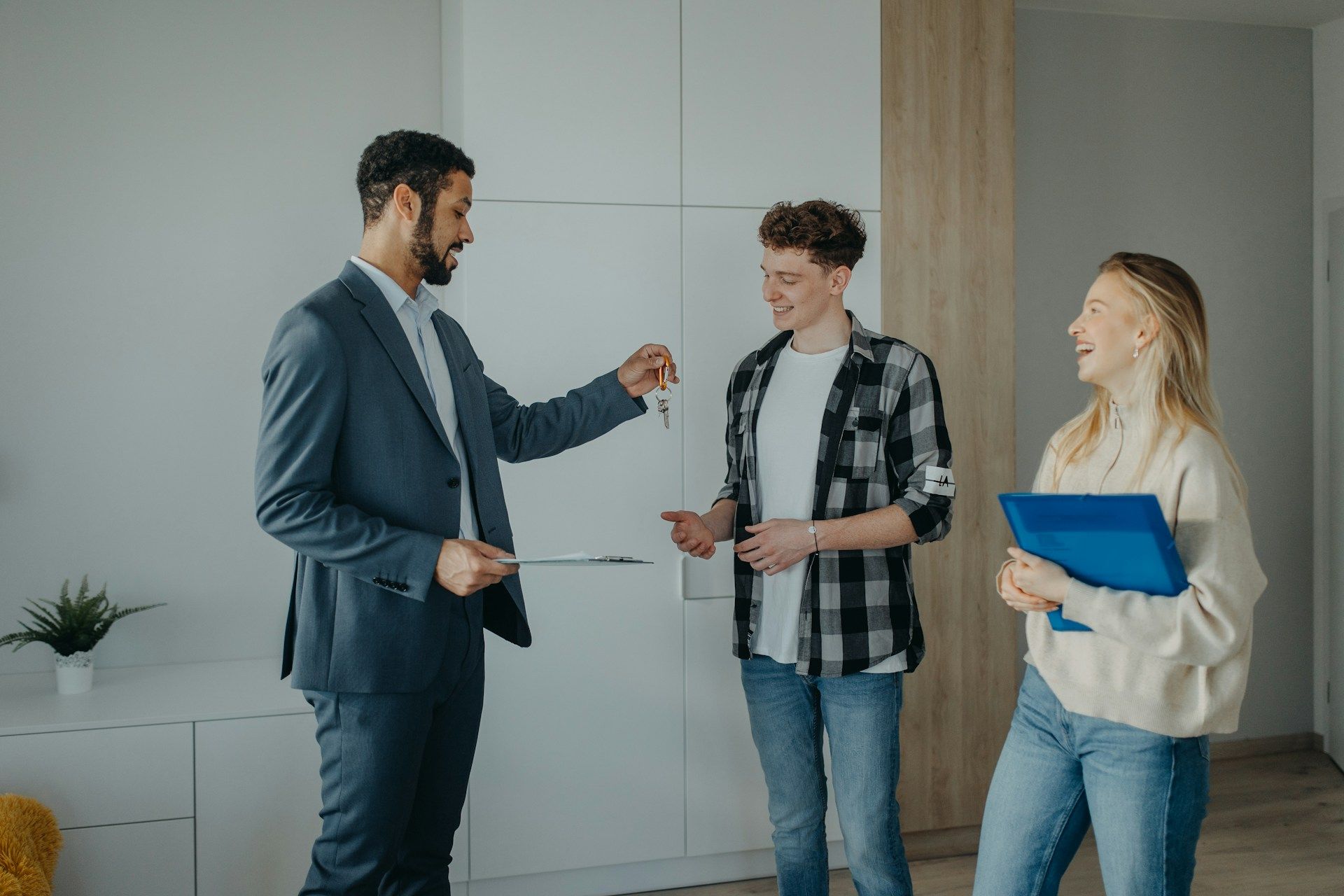 A realtor handing over the keys to a new home to a happy Edmonton couple