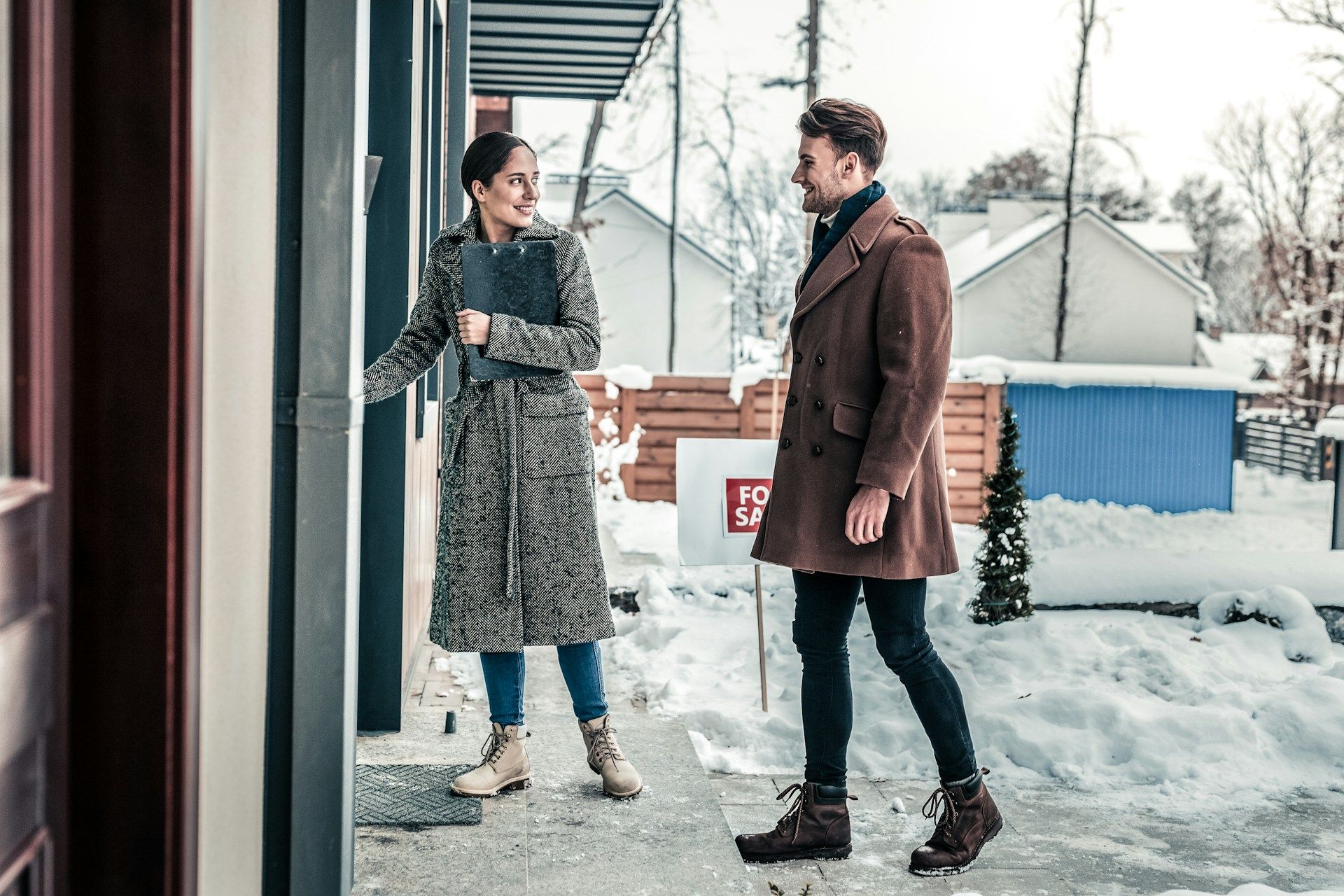 A female realtor showing a guy into a new home for sale during a snowy winter in Edmonton
