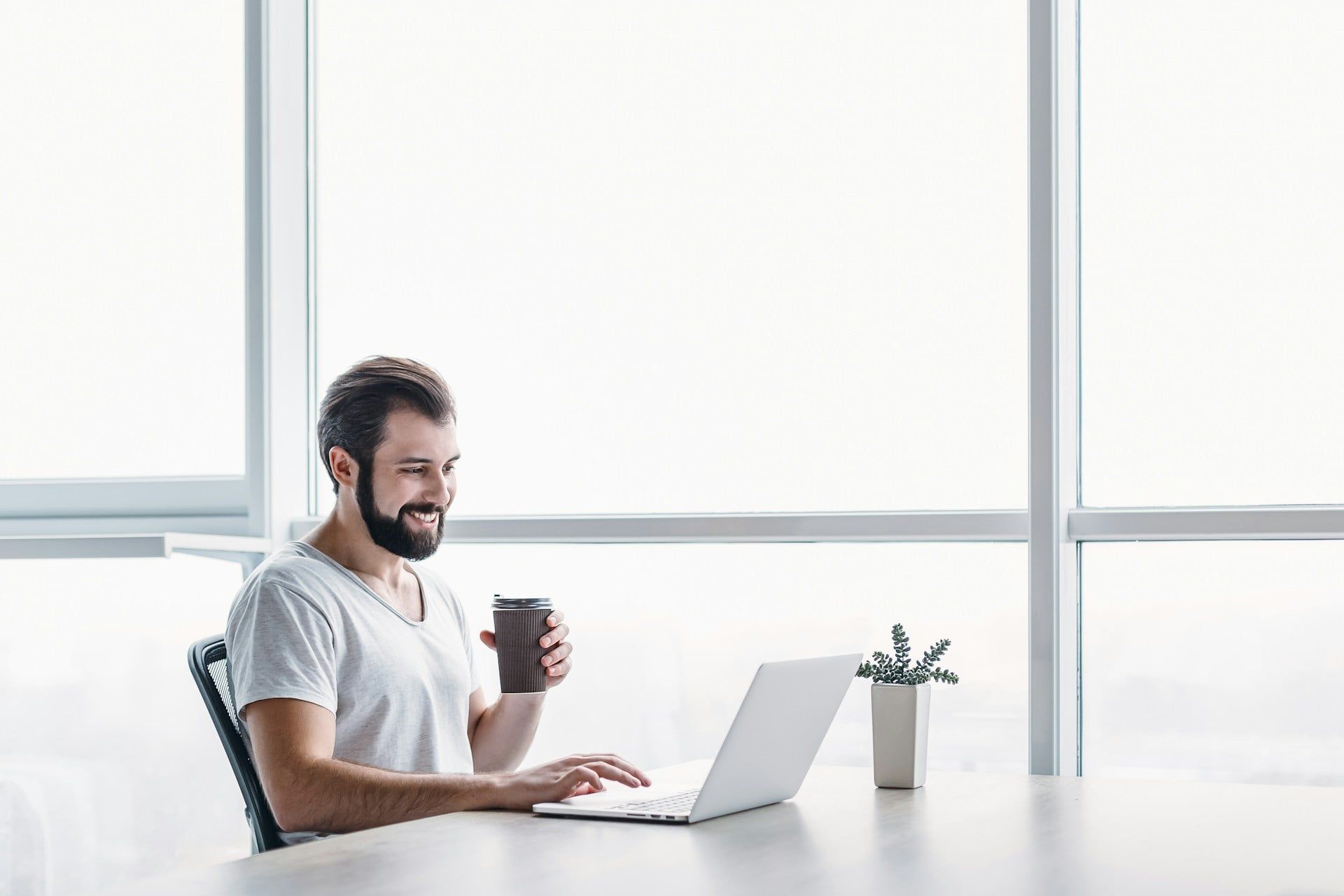 A male business owner sits at a laptop with a cup of coffee, smiling at how easy it is to set up a Google Business Profile.