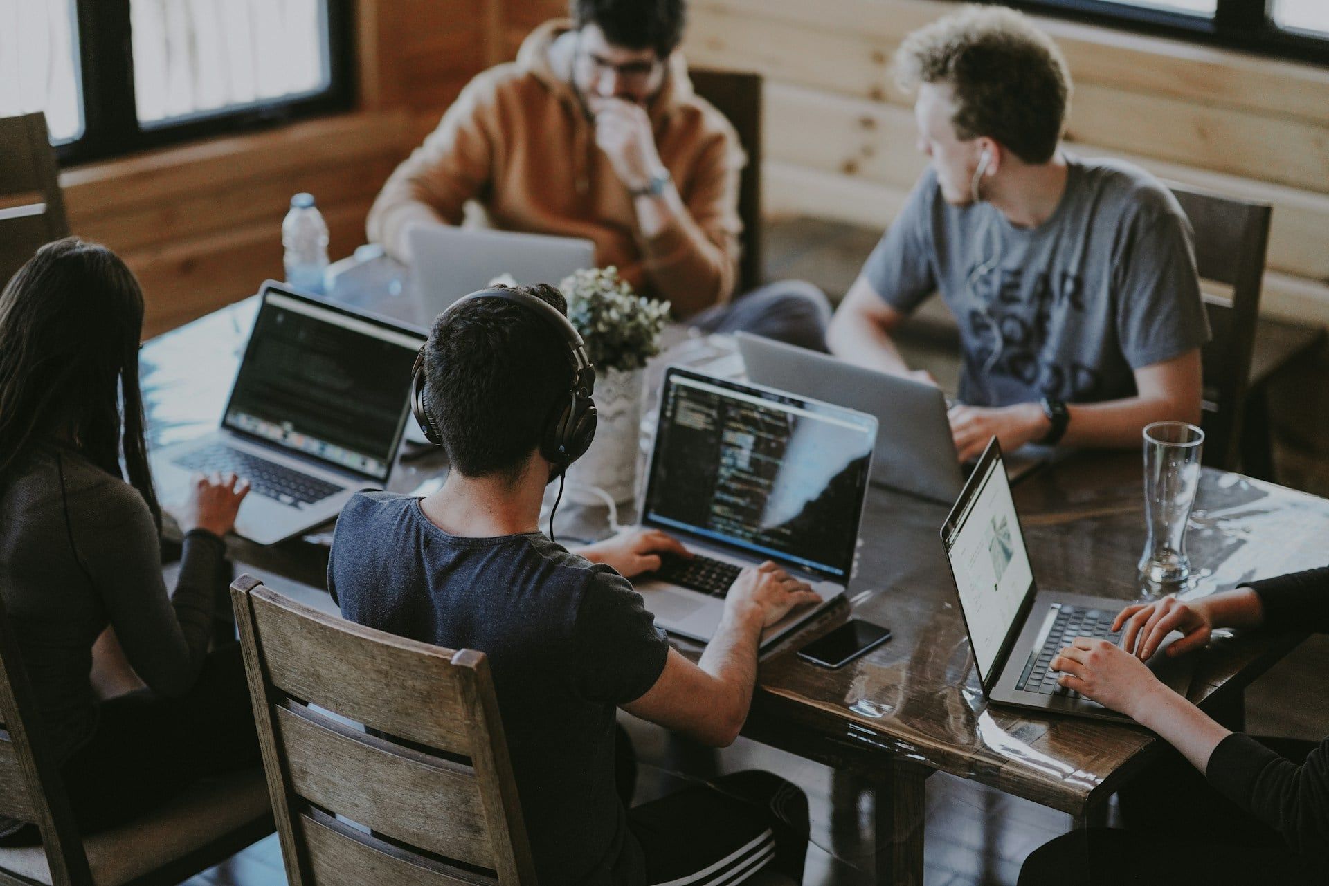 A small business office with a group of people on laptops working on a wooden desk