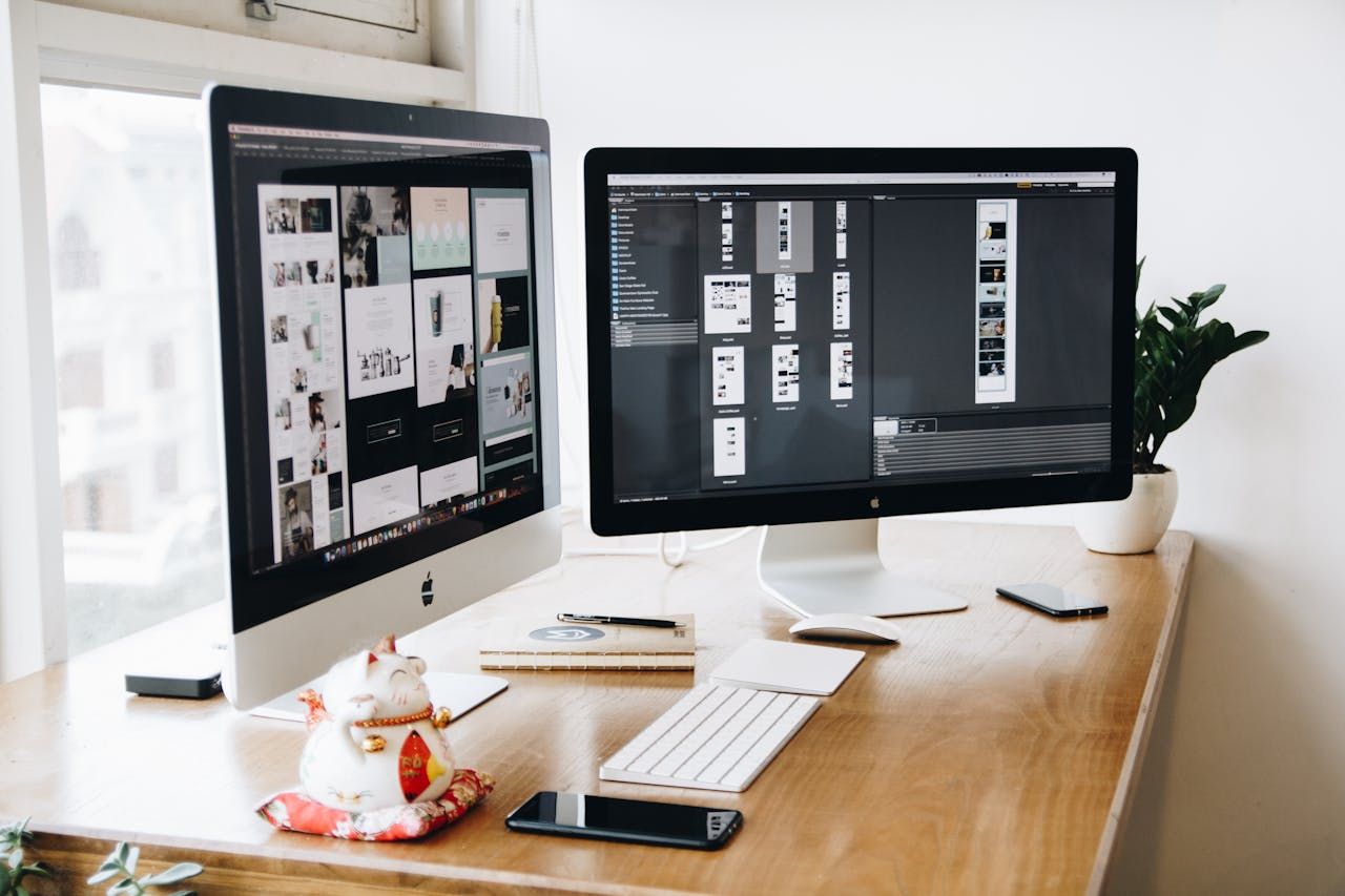 A dual-screen monitor setup with someone designing a new website