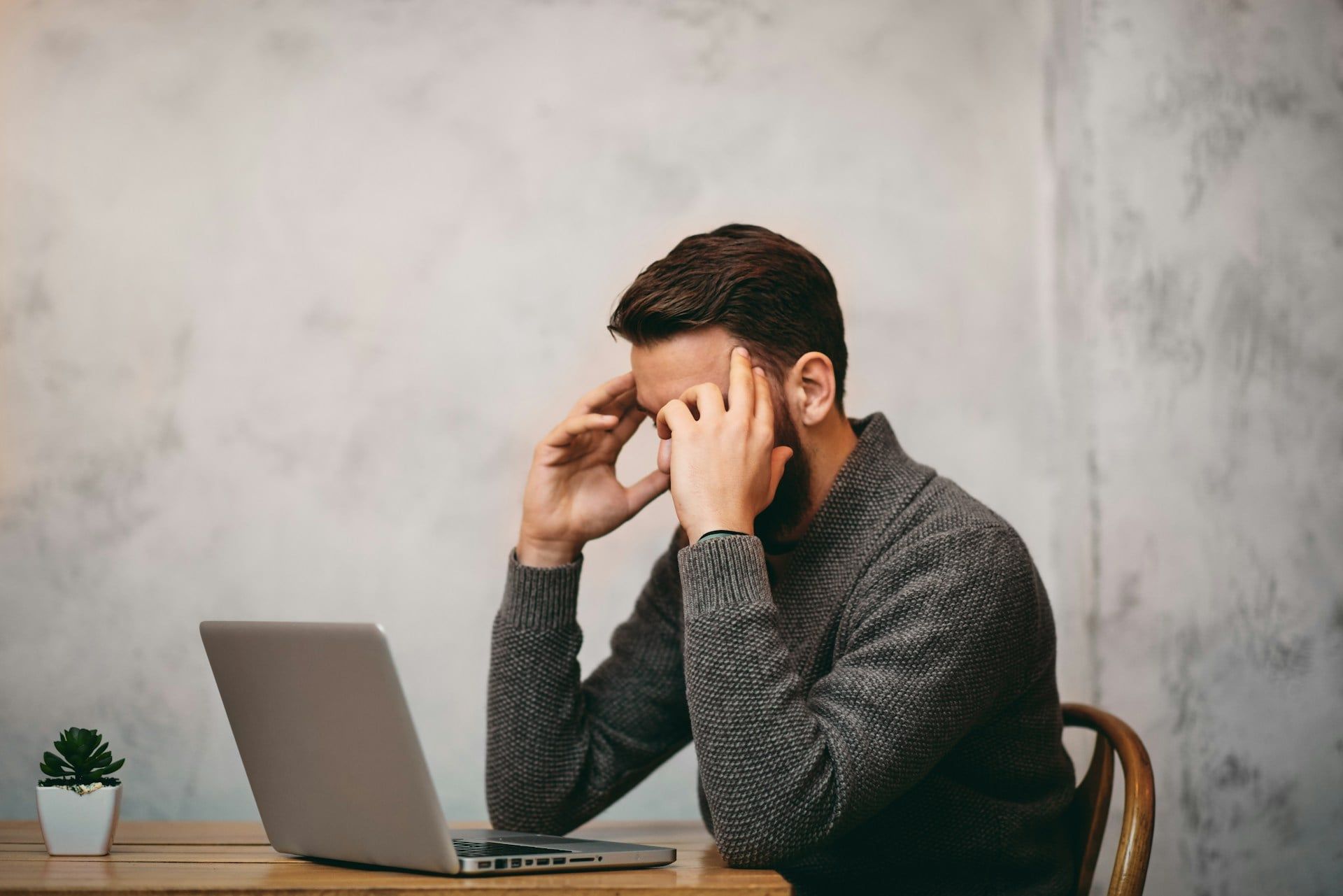 A guy sits at his laptop looking stressed over the state of his website