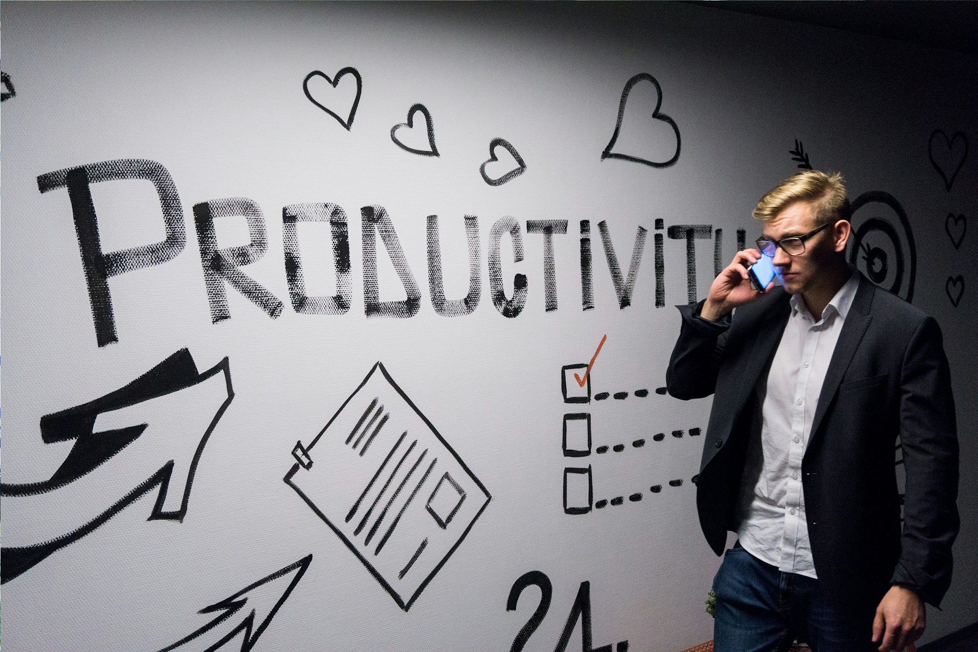 A man walks past a decorated wall with “productivity” written in big letters on it