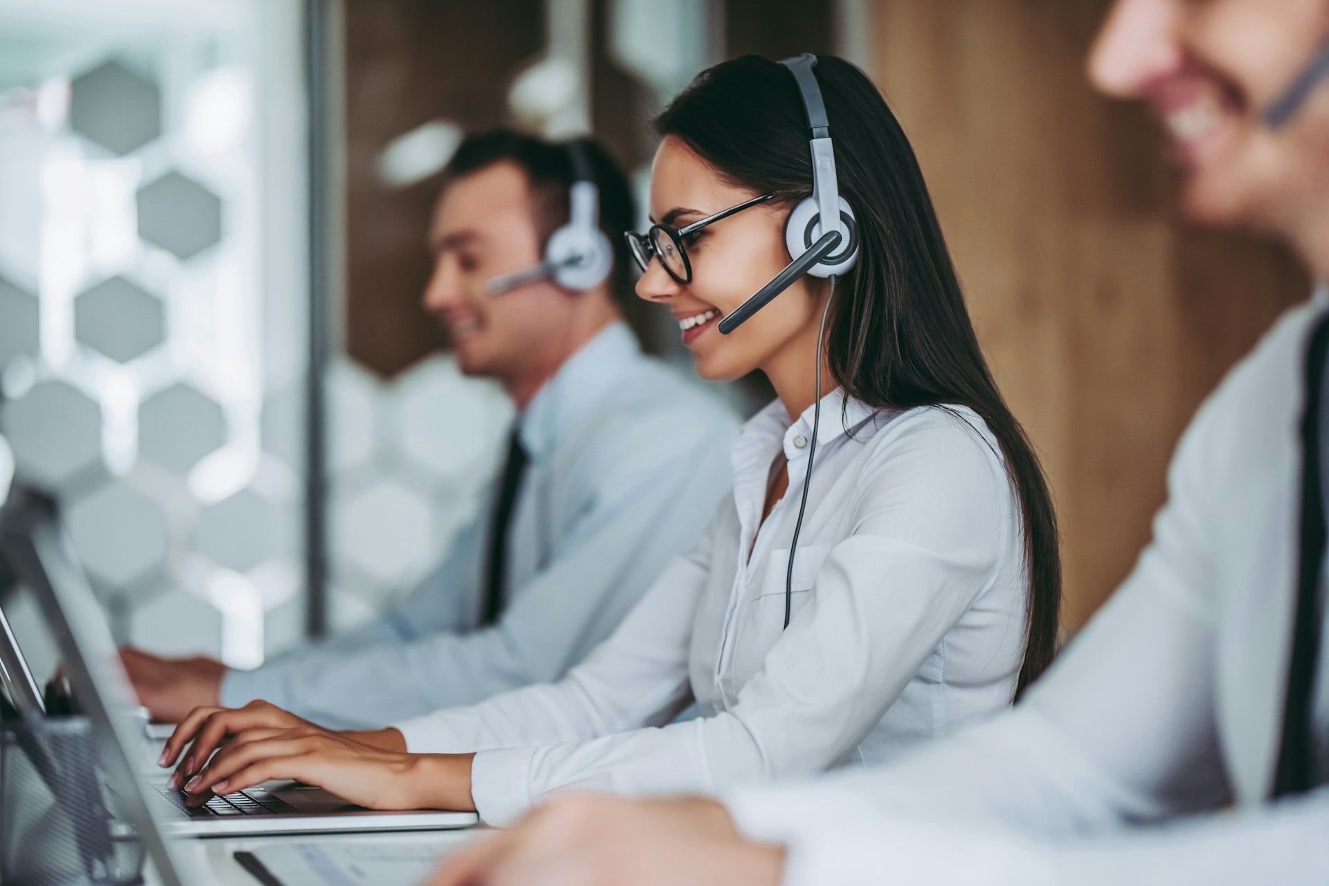 A row of live chat support agents in a traditional call centre setting