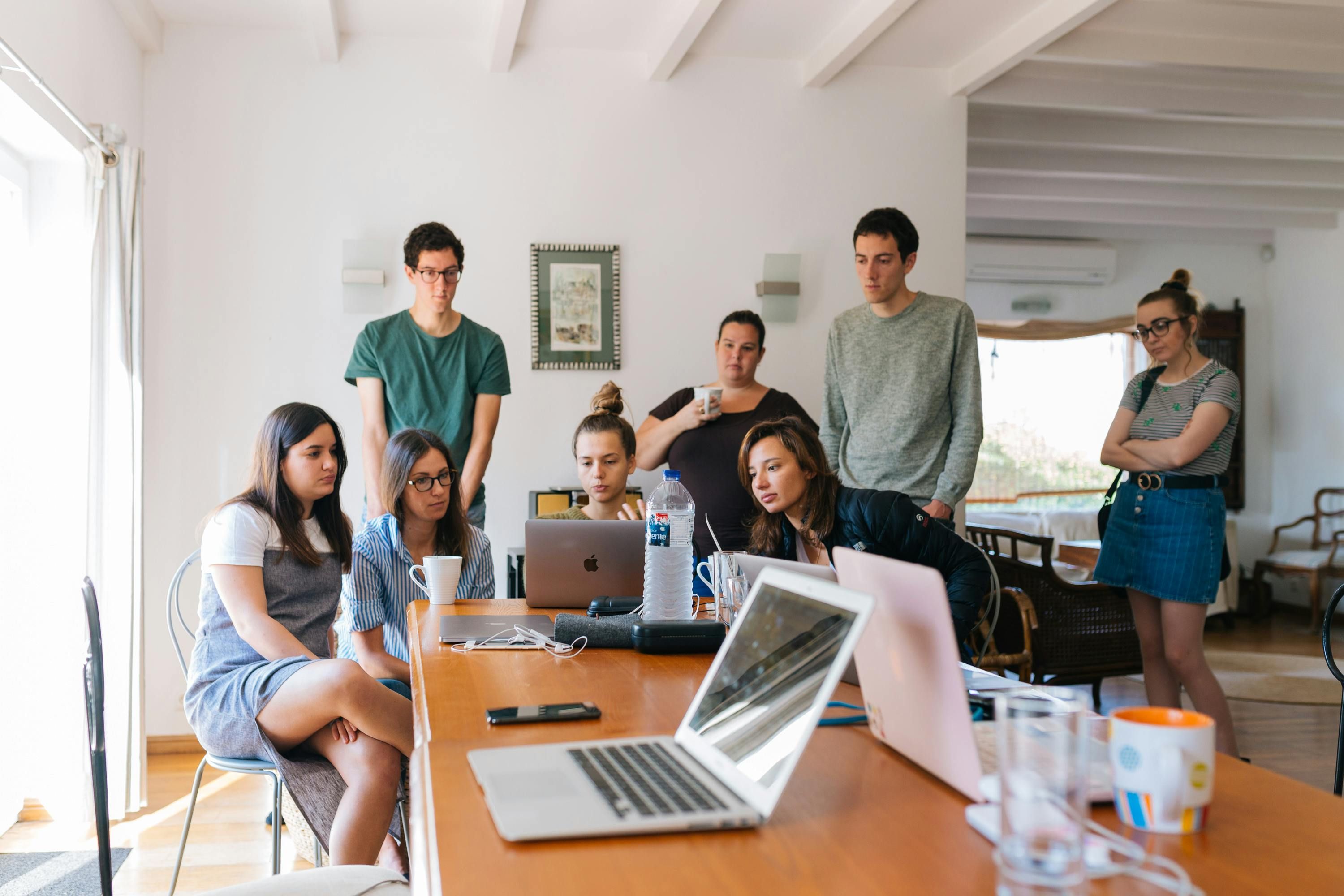 A small business team huddle around a laptop during a meeting