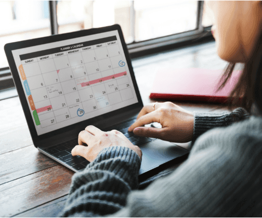 A female business owner fills out a calendar on her laptop, planning her business year