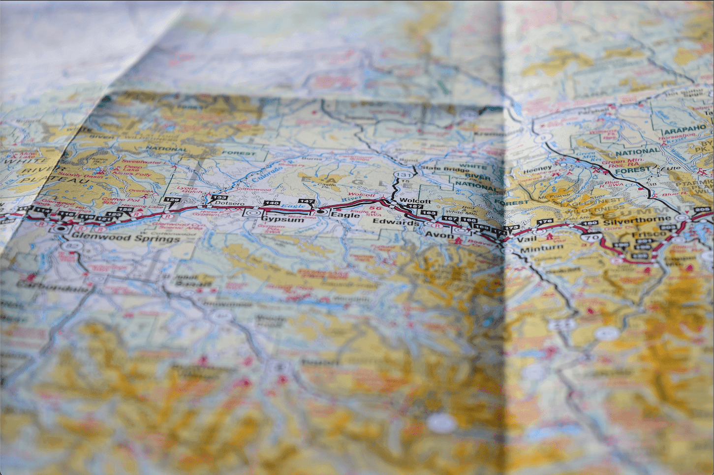 An aged, weathered map with faded parchment, intricate lines, and compass markings, hinting at ancient explorations and hidden treasures.