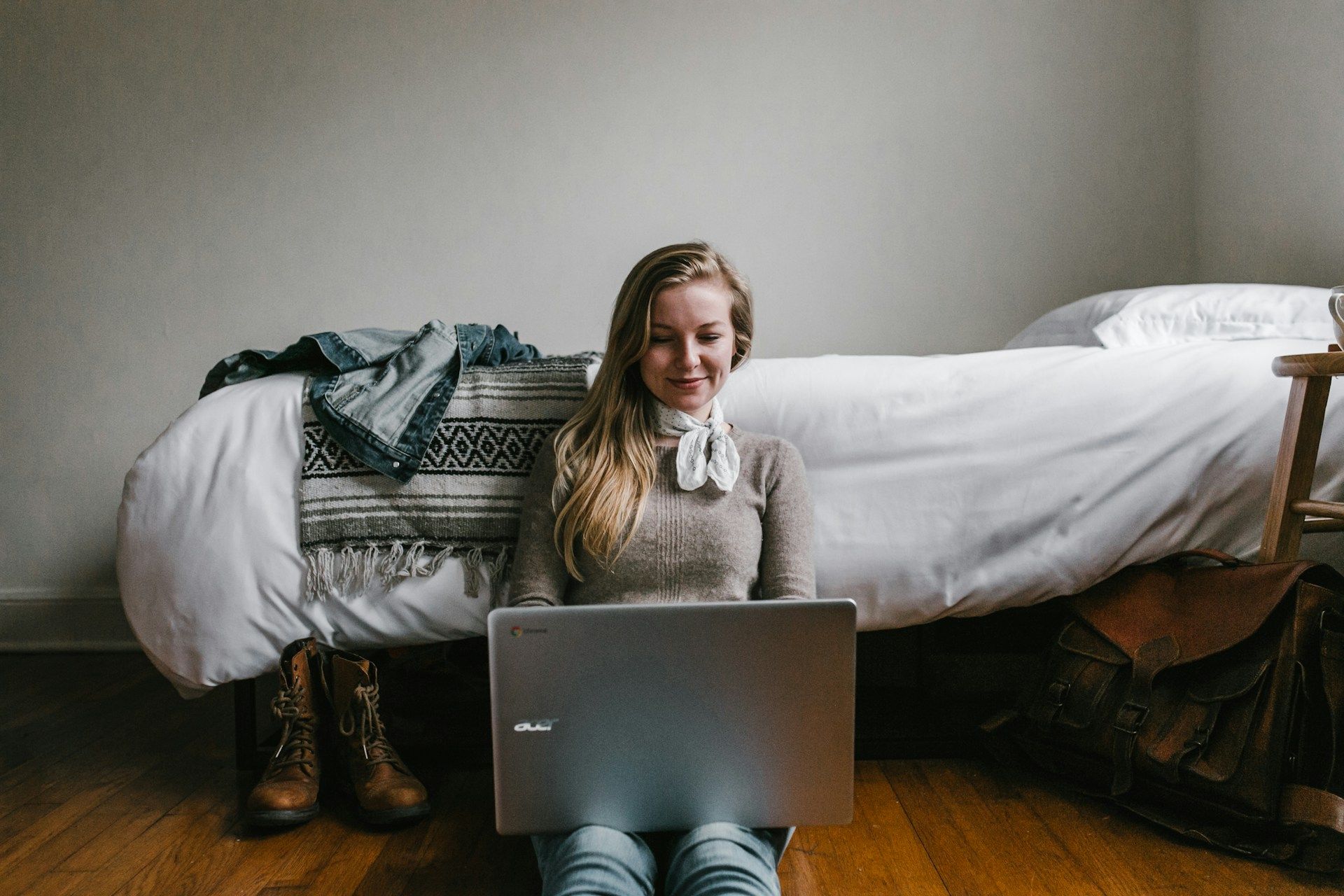 A woman sits on the floor using a laptop to browse businesses online