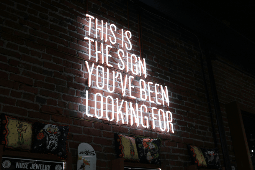A sign mounted on a brick wall with bold text that reads, 'This is the sign you've been looking for,' offering a playful and inspiring message.