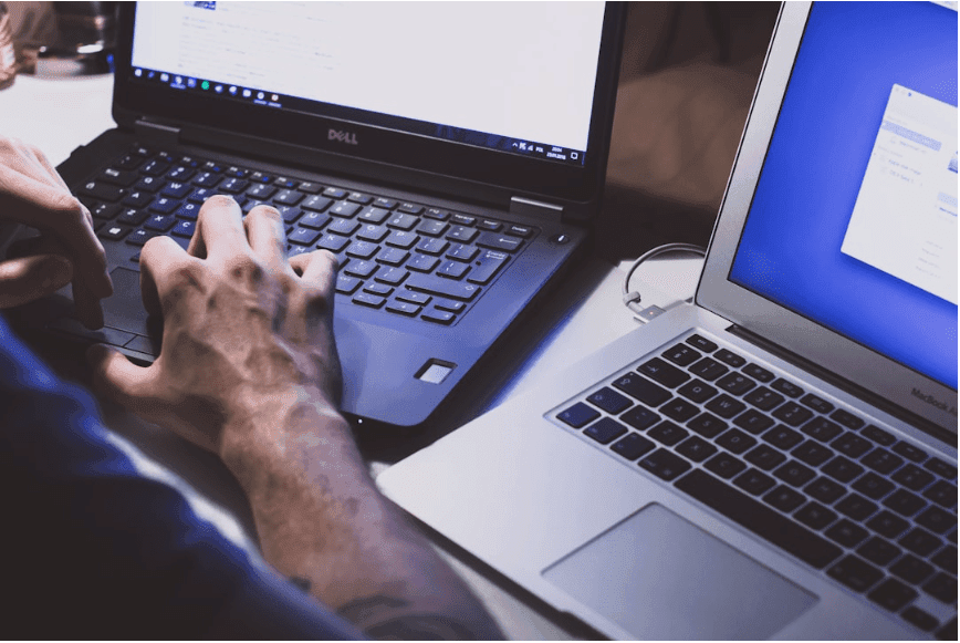A person working on two laptops simultaneously.