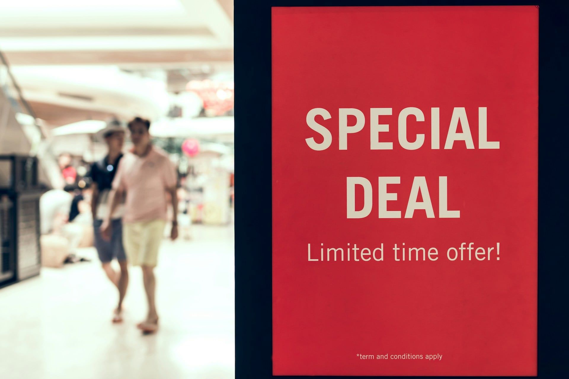 Two people walking through a mall with a sign in front that reads “Special Deal, Limited Time Offer”