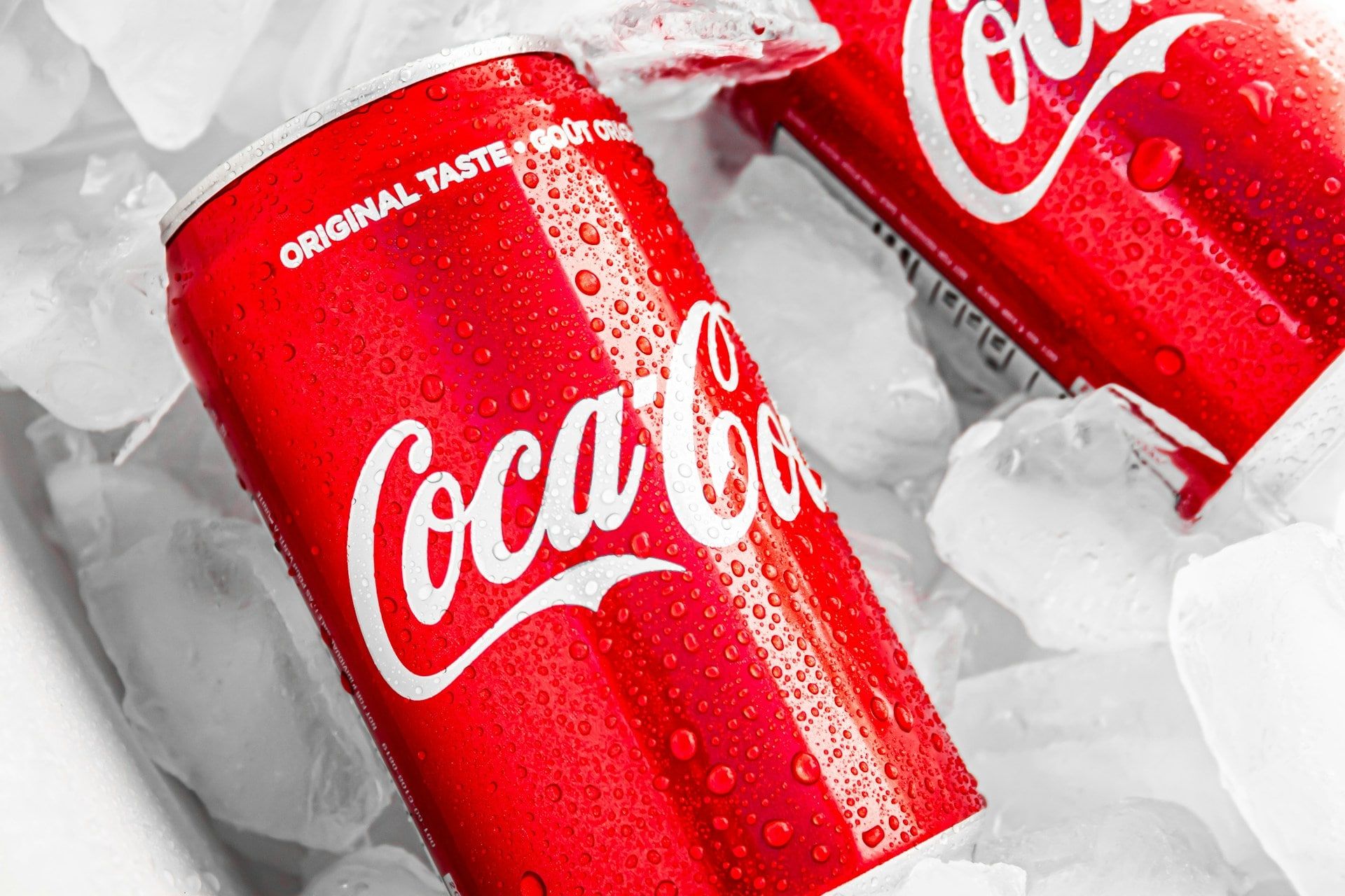 Two classic red Coke cans chilling in ice