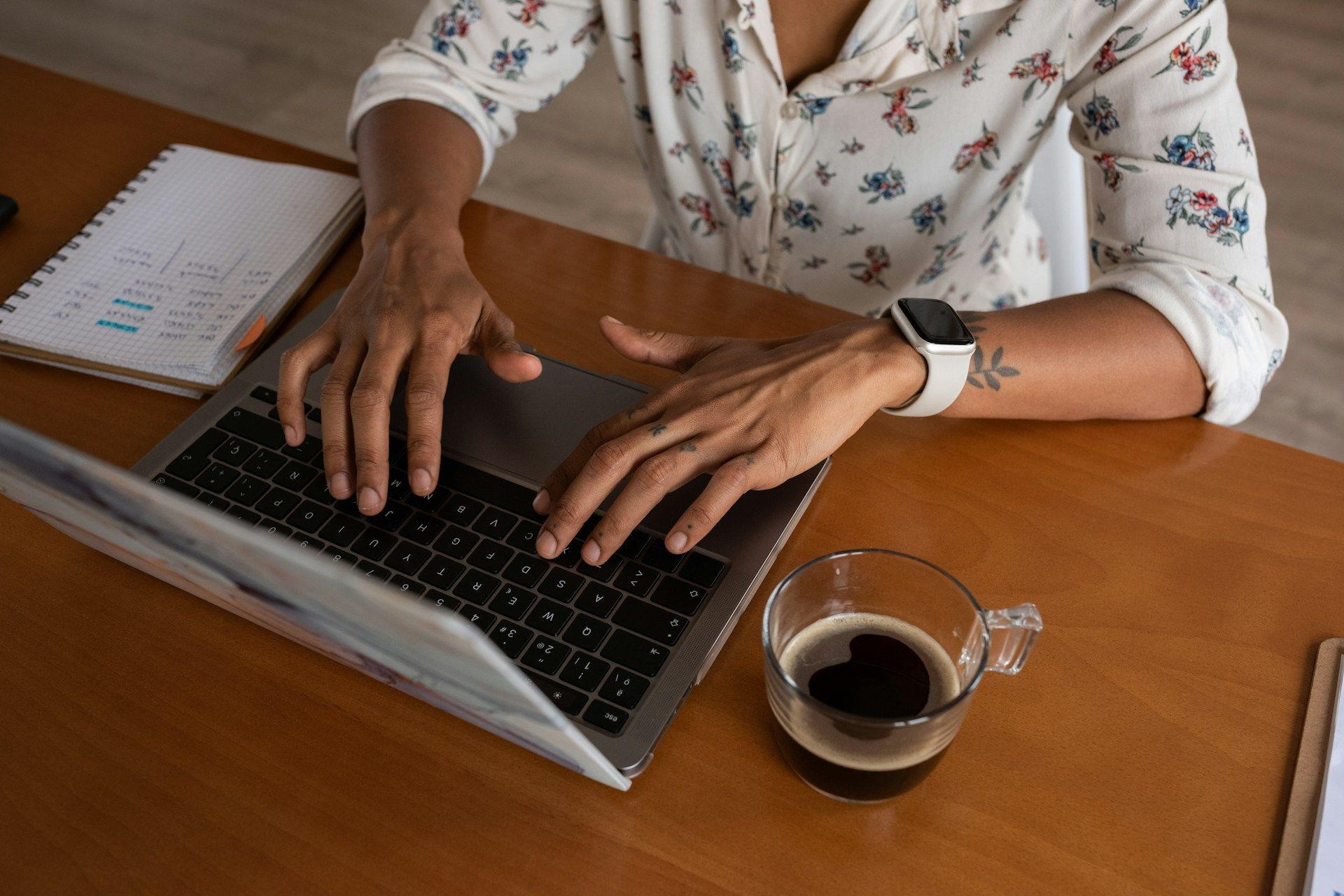 Someone sat at a desk writing blog content with a coffee
