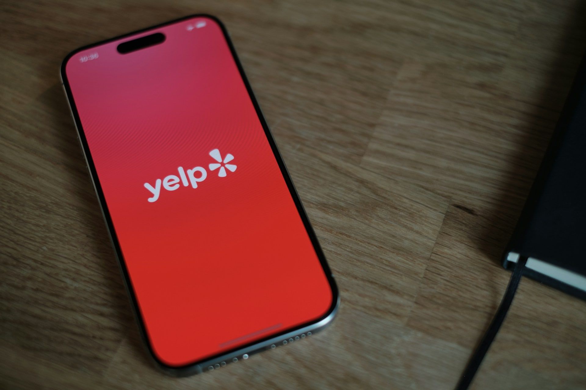 A smartphone on a desk with the Yelp app opening on screen