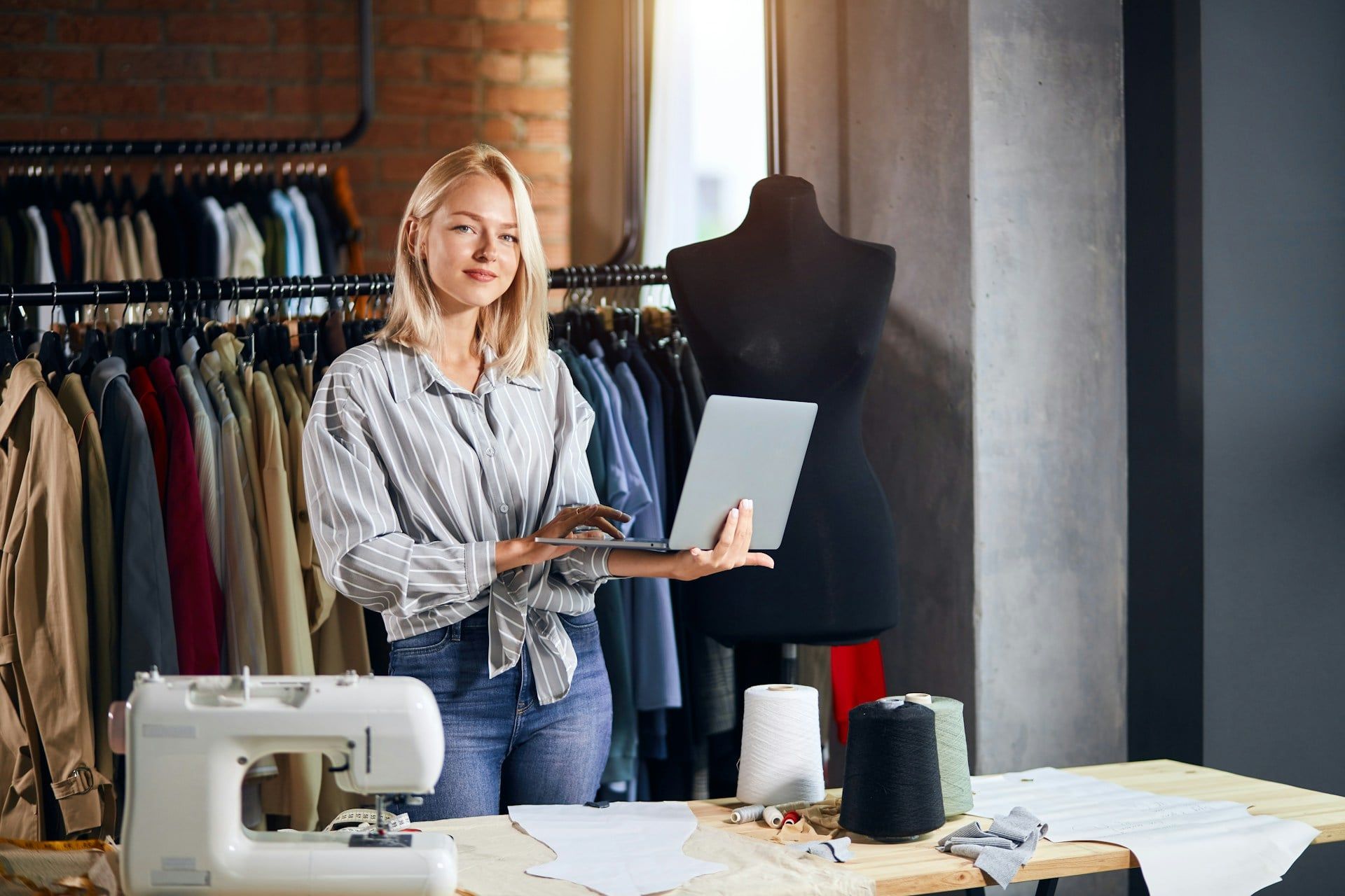 A small business owner standing in her studio holding her laptop