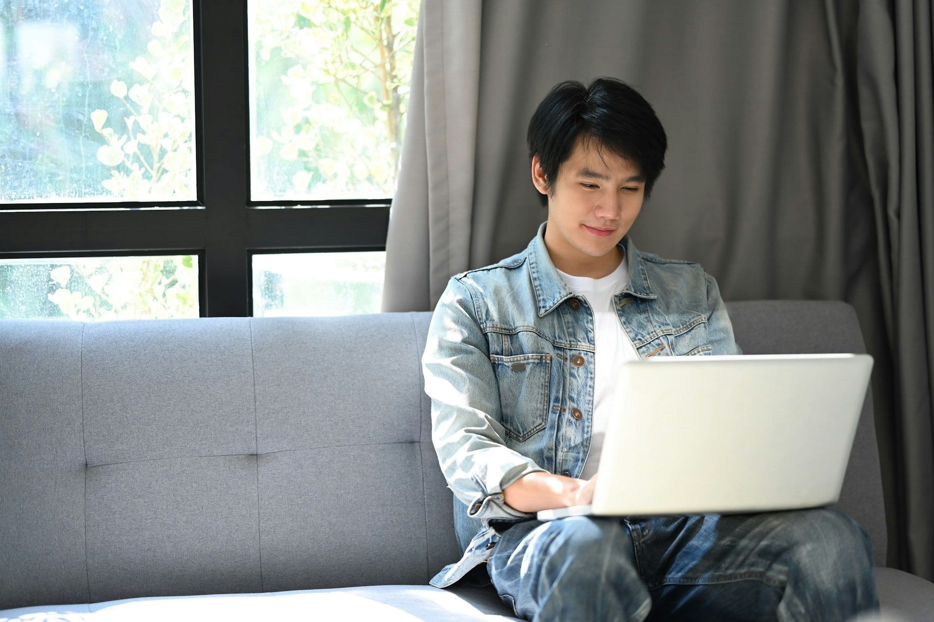 A guy sat on a couch using a laptop
