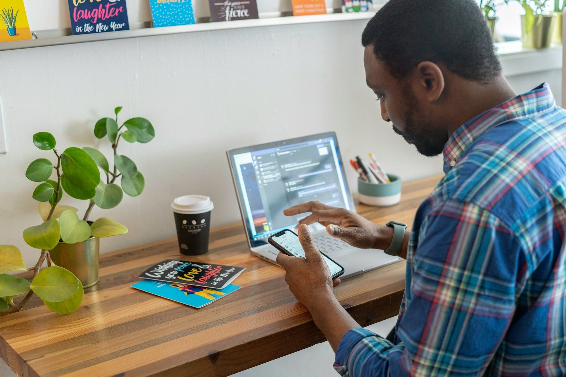 A man sits at his desk using his smartphone at work