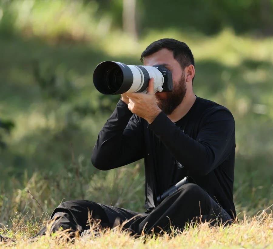 Biólogo operando câmera em margem de rio durante gravação de documentário
