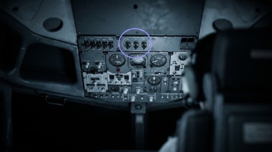 A cockpit overhead panel with one switch group ringed in violet