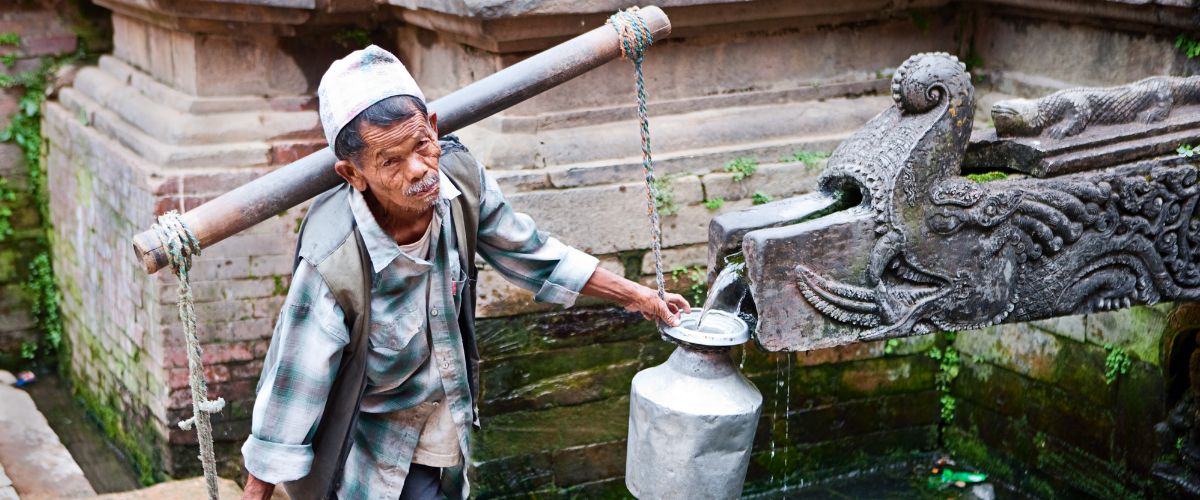Nepali old man filling brass jar