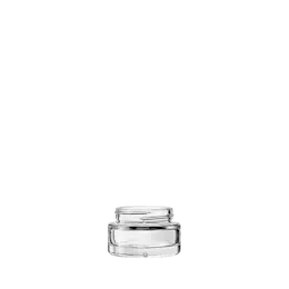 The image shows the Calaso 1.0oz Glass Jar. It is a small, cylindrical glass container with a clear, smooth surface. The jar has a wide mouth with a threaded neck designed to accommodate a screw-on lid, which is not shown in the image. The base of the jar is flat, allowing it to stand upright. The glass appears to be thick and sturdy, suitable for holding various contents.