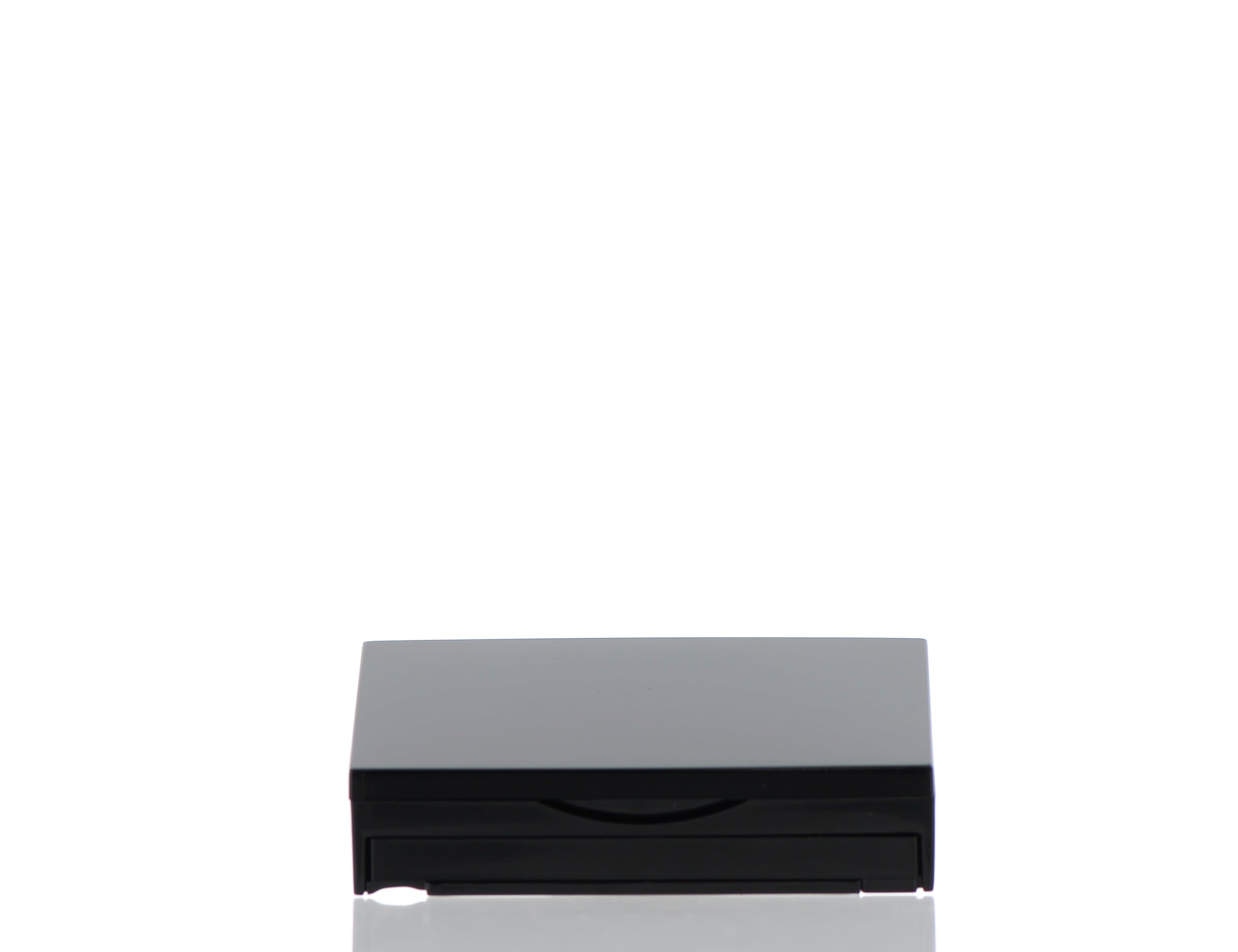 The image features the APG Packaging 0.0oz ABS Compact (APG-CT-S016-BK). The compact is circular with a sleek black exterior. The lid is closed, showing a smooth, shiny surface with no additional markings or designs. The compact's simple and elegant design suggests it is meant for holding makeup or similar products. The overall appearance is minimalist and modern.