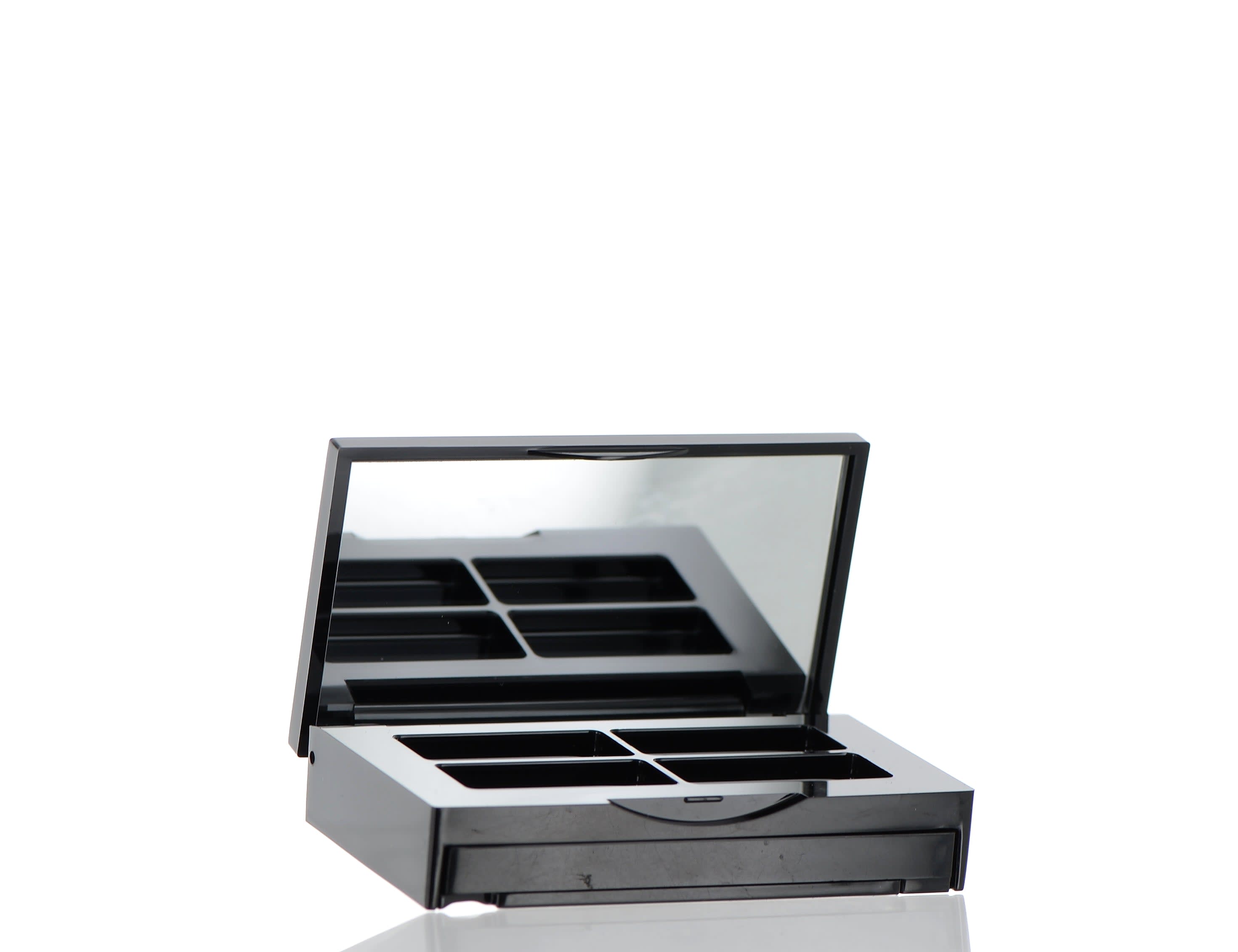 The image shows the APG Packaging 0.0oz ABS Compact (APG-CT-S016-BK). This is a sleek, black, rectangular compact case with rounded edges. The compact features a smooth, glossy finish on the exterior. The lid of the compact is closed, showcasing its minimalist and elegant design.